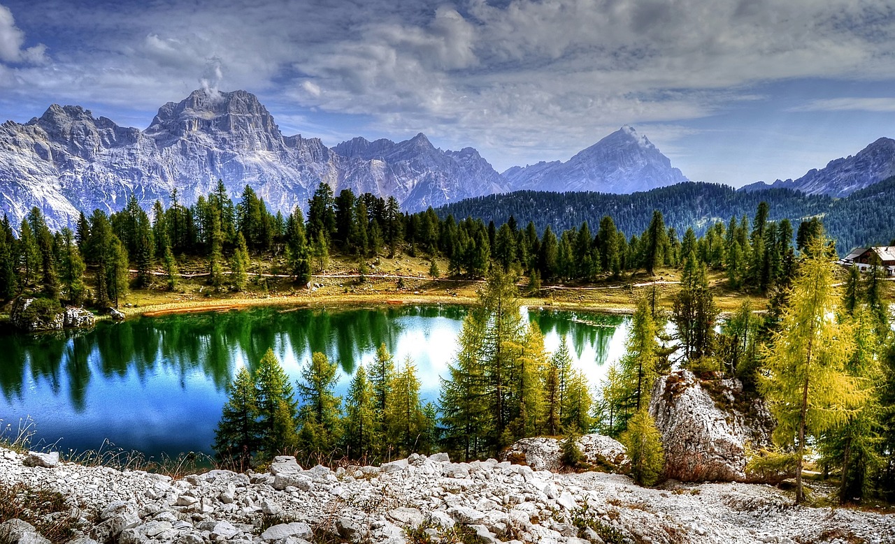 Lago di Sorapis con acque azzurro lattiginoso circondato da montagne e vegetazione.