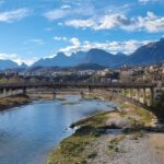 Vista panoramica di Bassano del Grappa con il Ponte degli Alpini e spritz in primo piano.