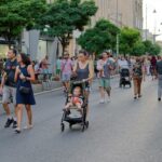 Passeggiata nel centro città, persone che esplorano strade pedonali e aree verdi.