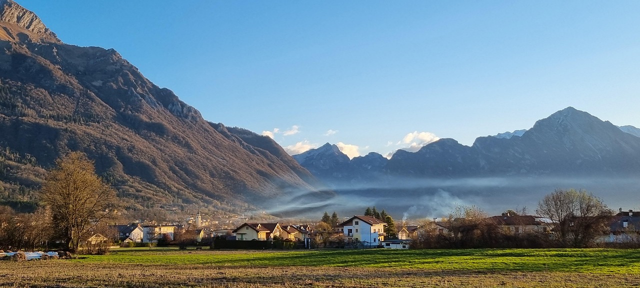 Panorama montano con cielo azzurro, case tradizionali e natura incontaminata nel paese descritto nell'articolo.