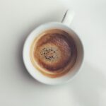 Tazza di caffè riscaldato con schiuma, evidenziando il cambiamento di colore e consistenza.